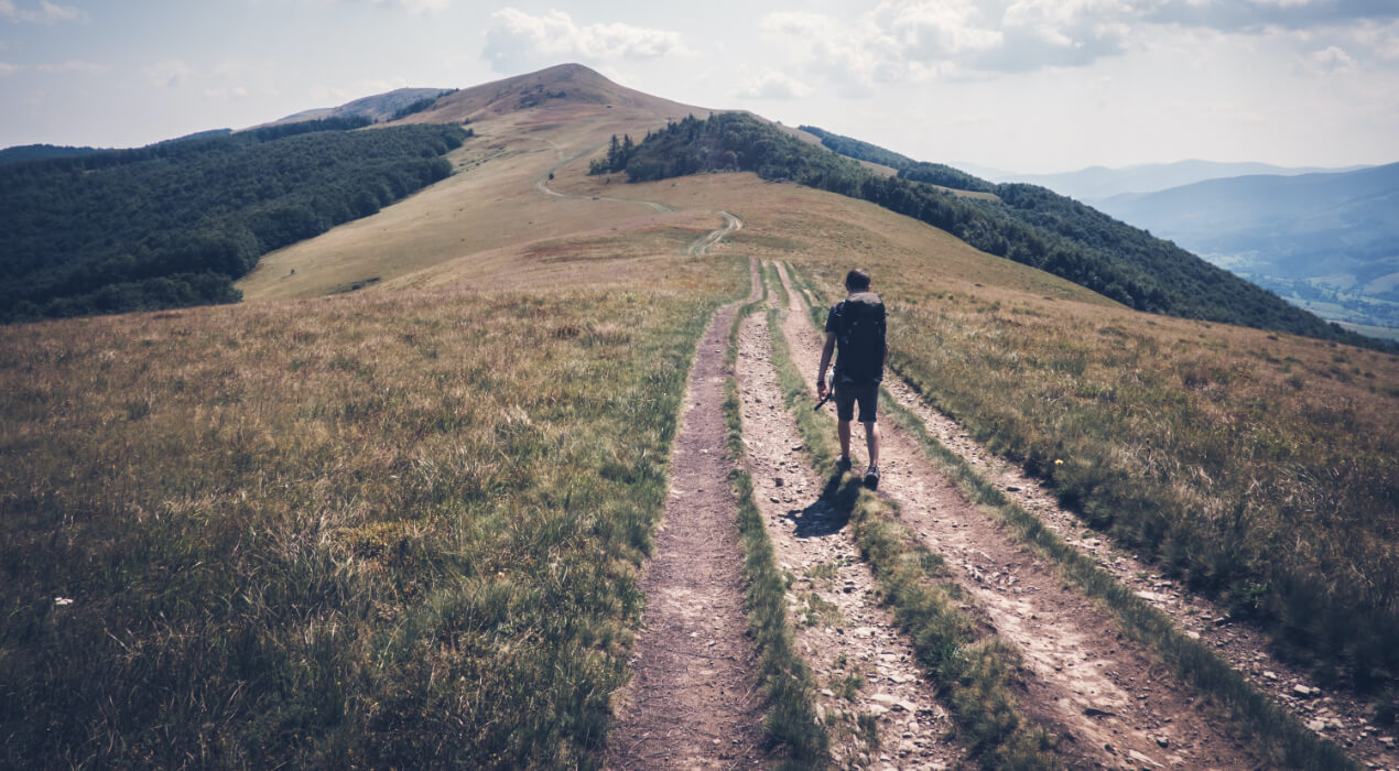 A man hiking down a long road in the mountains